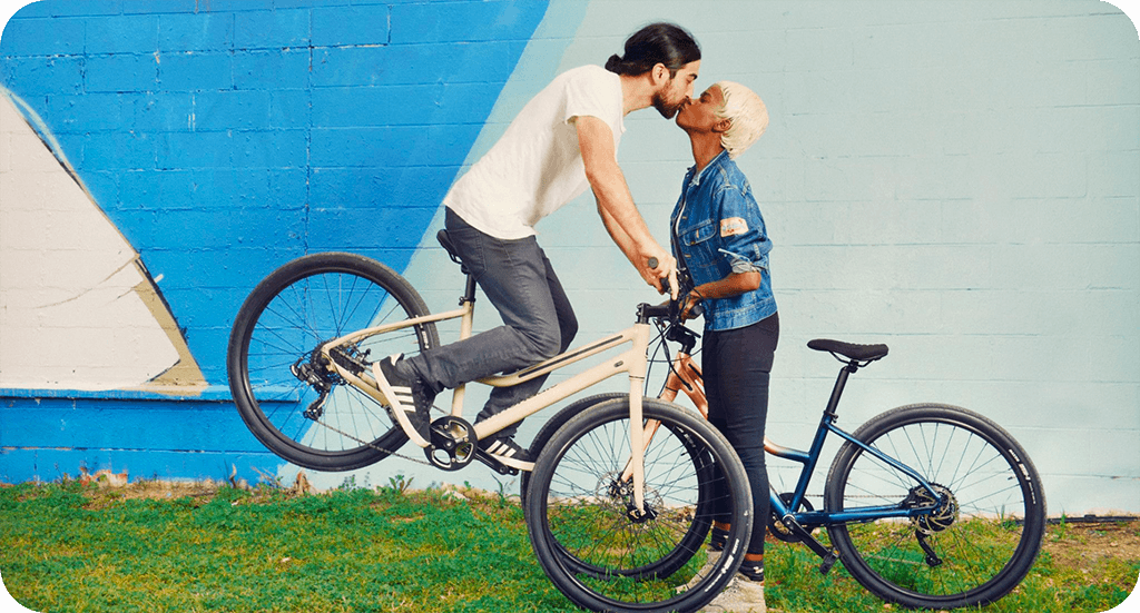Ett par på varsin cykel som pussas