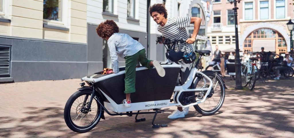 En man med ett barn på en lådcykel från Urban Arrow